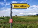 Gelbes Straßenschild der Römersiedlung Friesenheim mit der Aufschrift Römersiedlung.
