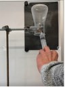 Ein umgekehrt aufgehängter Erlenmeyerkolben, dessen Öffnung nach unten zeigt, ist sicher in einer Stativklemme befestigt. Eine Spritze mit einer langen Kanüle ist eingeführt, um Wasserstoff in den Kolben zu injizieren.
