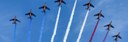 mehrere Kunstflugzeuge fliegen versetzt nebeneinander und hinterlassen Kondenzstreifen in den Farben der französischen Flagge