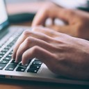 Hände auf einer Laptoptastatur