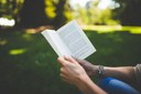 Frau, die im Park sitzt und ein Buch liest, mit Fokus auf den Händen